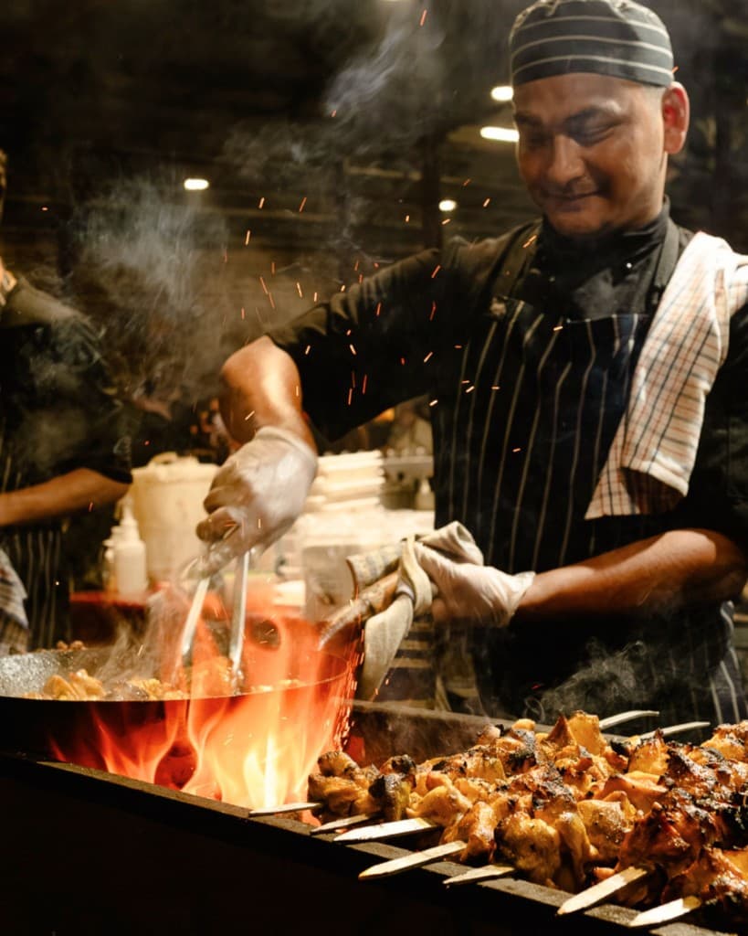 Chef stir-frying in a wok over open flame at a night market