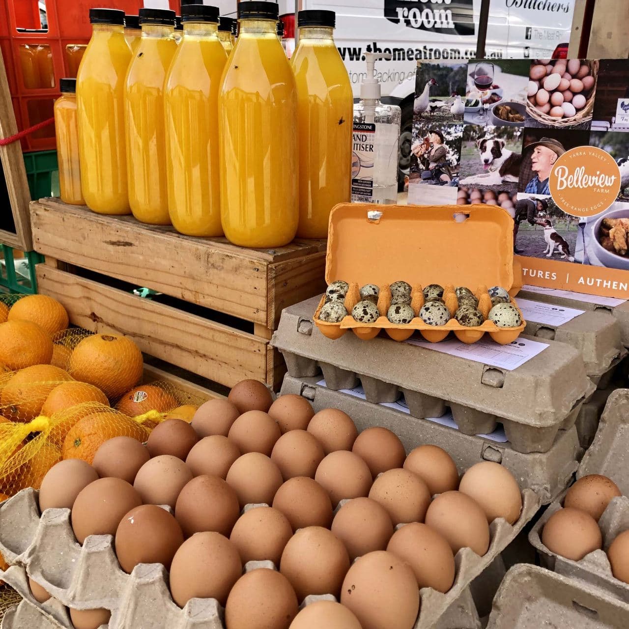 Eggs, fresh juice, and produce at a farmers market stall